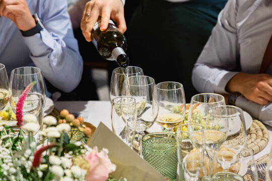 Close-up of white wine being poured into glasses at an elegant business event or corporate dinner table setting.