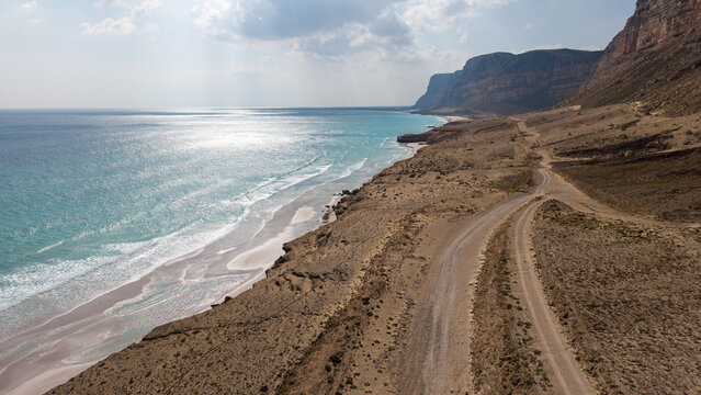 Drone view of desert coastal road by turquoise sea. Sokotra, Yemen.
