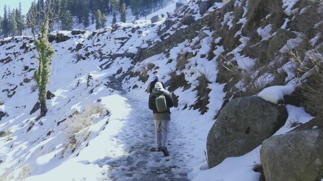 Two Men Walking on Snowy Mountain Trail Taking Photos Near River in Jammu and Kashmir, India