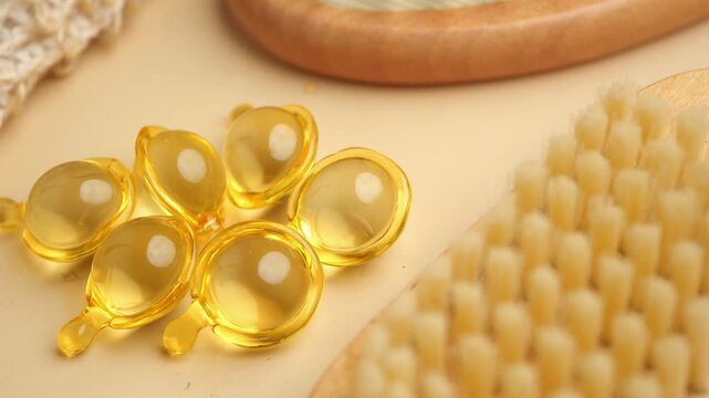 Close up shot of golden vitamin e oil capsule and bath brush for skin on white background.