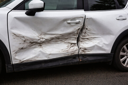 Severe Impact Damage on Side of White Vehicle, Crumpled Doors After Accident