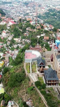 Aerial drone view of Rova of Antananarivo royal palace complex, perched above the city and surrounded by tightly packed houses on the hillsides of Madagascar's capital. Vertical