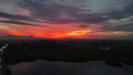 Fototapeta premium Dramatic Sunset Sky Over Mountains, Town, and River Landscape