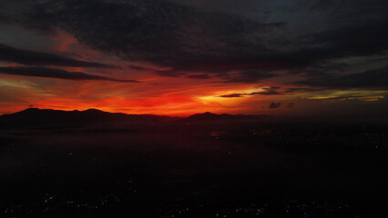 Fototapeta premium Dramatic Fiery Sky Over Mountain Silhouettes at Sunset or Sunrise