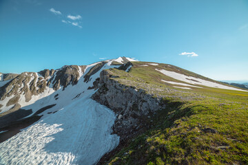 Scenic view above rocky ridge with cliff and snows against pointy peak. Alpine scenery with sharp rocks, sheer crags and peaked top. Tectonic plate protruding from an abyss. Stony pointed pinnacle. © Daniil