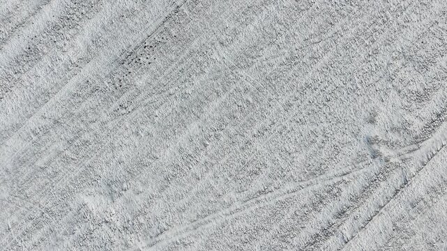Snowy farm field showing geometric tractor track patterns