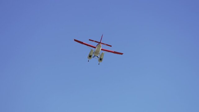 A floatplane flying through the blue sky in slow motion.
