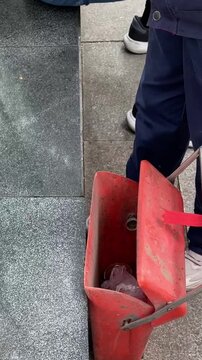 A scene of environment maintenance at Beijing Zoo using a long litter picker to remove trash and placing it into a red bin. Concept of environmental protection, public service, and park cleanliness.
