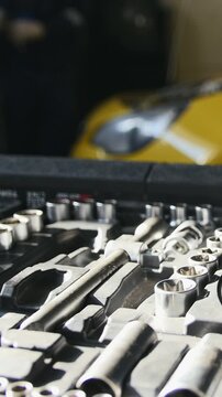 Mechanic repairs yellow car in professional auto service, de-focused time-lapse