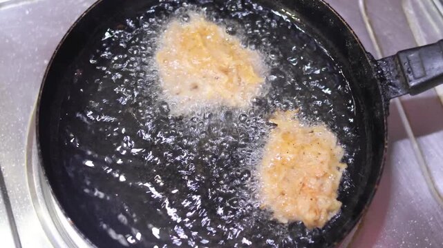 Sizzling view of savory potato dumplings frying in a pot of hot cooking oil.