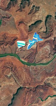 Bird's eye view on potash ponds, red rocks, deserted dry area with canyon of a river. Camera is zooming in, rotating counterclockwise. Vertical video. Animation based on image by NASA