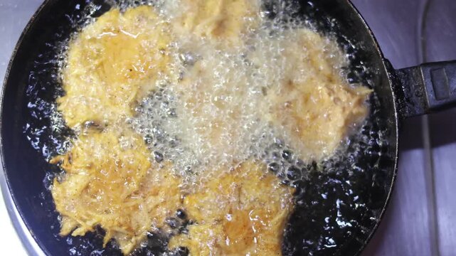 Delicious potato bondas being deep fried to a crispy texture for an authentic Indian appetizer.