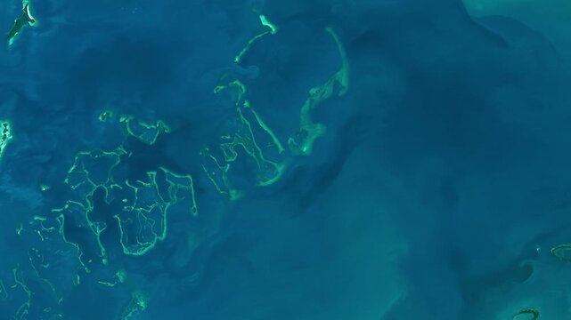 Bird's eye view on atolls in azure sea in tropical area. Camera is moving left. Animation based on image by NASA