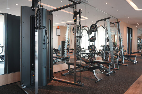 Modern gym interior featuring various strength training equipment including cable machines and weight benches