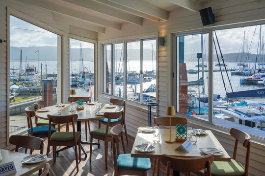 South Africa,Knysna Lagoon,Dining area with large windows overlooking a marina filled with boats and yachts on a sunny day