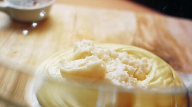Glass bowl with sour cream receiving a portion of lard
