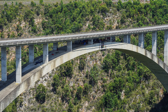 South Africa,Bloukrans Bridge,Aerial view of a concrete arch bridge spanning a forested valley with a vehicle crossing
