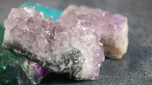 Beautiful purple amethyst clusters and green fluorite crystals rotating slowly on surface.