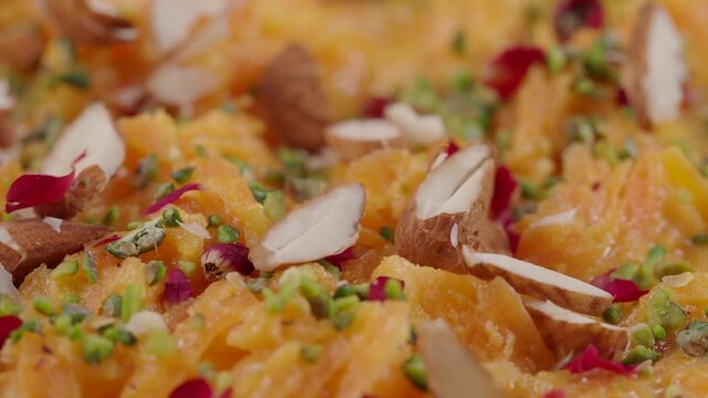 Almonds and pistachio flakes falling on a bowl of traditional indian dessert gajar halwa.
