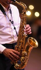 Obraz premium Close Of Individual Playing Saxophone To Live Performance Rehearsal Setting Main Subject Whose Face Partially In Background Wears White Shirt Dark Trousers Holding