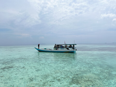 Karimun Jawa, Indonesia: Traditional Wooden Boat Floating on Crystal Clear Tropical Sea, Scenic Ocean View with Calm Water for Travel Tourism, Marine Adventure, and Relaxing Island Vacation
