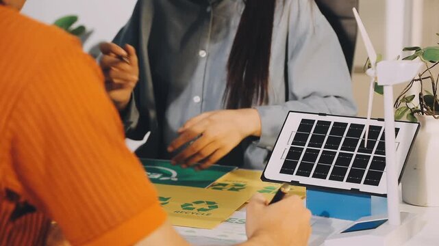 Business executives collaborating on environmental sustainability strategy utilizing renewable energy solutions to achieve net zero targets in corporate meeting.