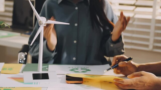 Business executives collaborating on environmental sustainability strategy utilizing renewable energy solutions to achieve net zero targets in corporate meeting.