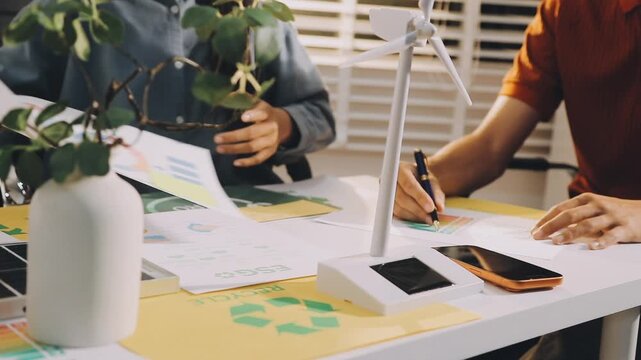 Business executives collaborating on environmental sustainability strategy utilizing renewable energy solutions to achieve net zero targets in corporate meeting.