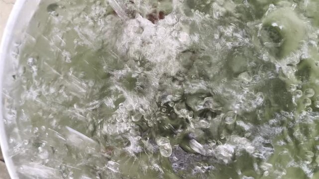 Rain fell on the water in the tank, creating ripples and waves that reflected the light