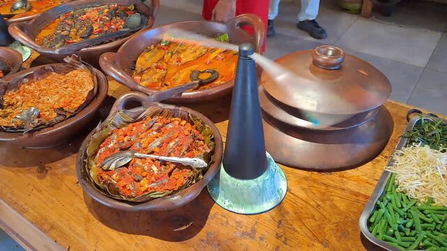 PAMEKASAN, INDONESIA - DECEMBER 17, 2025: Handheld footage inside a traditional Javanese joglo-style restaurant, showcasing authentic Indonesian cuisine, local vegetables, fish dishes, sambal, lalapan