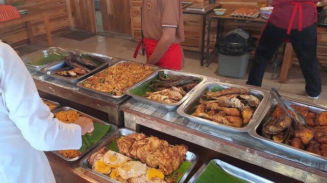 PAMEKASAN, INDONESIA - DECEMBER 17, 2025: Handheld footage inside a traditional Javanese joglo-style restaurant, showcasing authentic Indonesian cuisine, local vegetables, fish dishes, sambal, lalapan