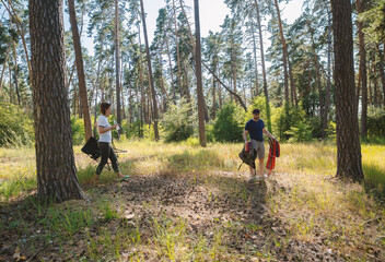 Fototapeta premium Young Couple Setting Up Camp in Sunny Pine Forest with Hammock and Chair