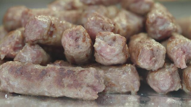 Freshly grilled cevapcici sausages piled on kitchen counter for serving in local restaurant.