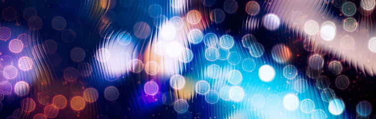 Abstract panoramic background with colorful bokeh lights and wavy glass texture. Defocused glowing circles