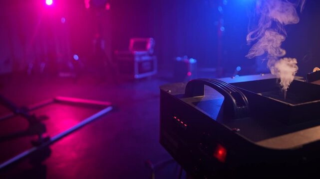 Stage fog machine with smoke and camera slider on a dim backstage set with colorful lights and camera equipment. Concept of concert production, theater effect, filming, entertainment, event technology