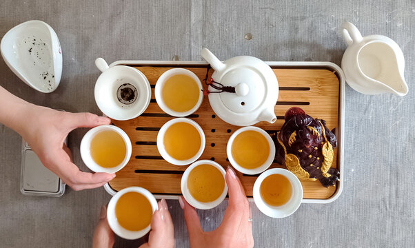 Traditional chinese tea ceremony gongfu cha with white ceramic teapot, cups and golden money frog on bamboo tray. Pouring oolong tea, mindful atmosphere, oriental culture and zen lifestyle.