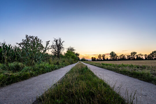 Gerader Feldweg bei Sonnenuntergang &ndash; Landschaft in l&auml;ndlicher Umgebung