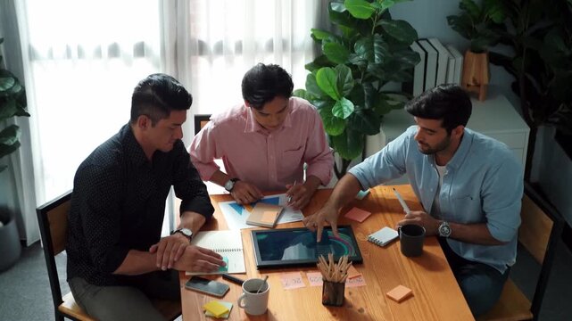 Top view of businessman looking and analysis financial graph from tablet at meeting. Group of diverse people brainstorming and planning strategy while taking a note by using sticky notes. Convocation.