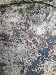 Fototapeta premium Close-up of weathered stone surface with dark natural texture and organic patterns formed over time, stone wall texture