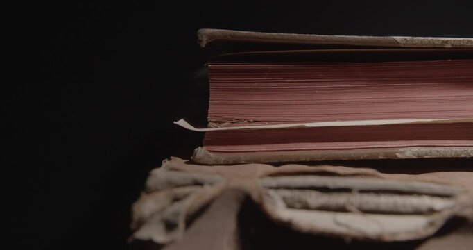 Closeup of pages of an old weathered vintage book in local light. Historical knowledge archive library concept. Slider macro 4K video. 