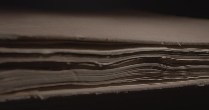 Closeup of pages of an old weathered vintage book in local light. Historical knowledge archive library concept. Slider macro 4K video. 