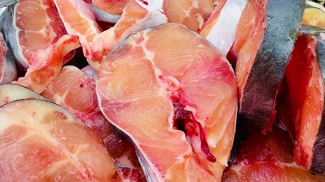 A close-up image of a slice of fresh Striped catfish, or Sutchi catfish, shows its natural texture and color. The raw fish slices, prepared for cooking, display the succulent flesh, and a cross-sect