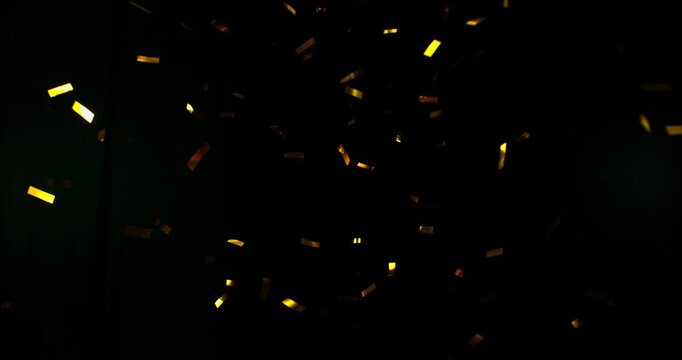 Golden confetti flying in super slow motion against a black background. Shiny metallic particles drifting and falling in the air, creating elegant festive atmosphere with dramatic lighting.