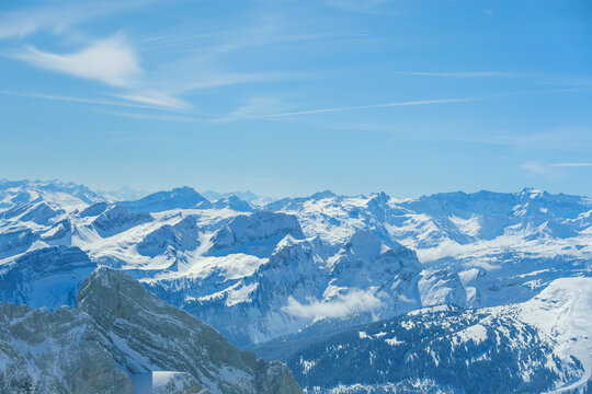 Snow covered mountain range under clear blue sky, showcasing majestic peaks and serene winter landscape. vast expanse of snow and ice creates tranquil and breathtaking view