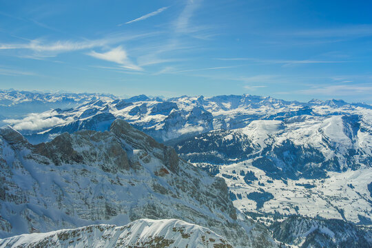 Snow covered mountain range under clear blue sky, showcasing rugged peaks and expansive valleys. serene landscape captures beauty of winter in remote, alpine region