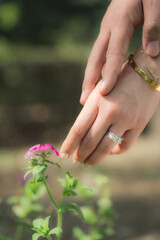 Fototapeta premium Indian traditional engagement ceremony exchanging wedding rings, Bride's hands with henna and bangles placing a ring on groom's finger.