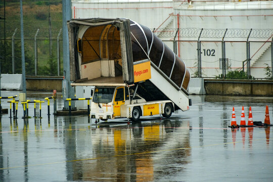 An enclosed airport passenger stairway truck parked safely on the rain soaked tarmac prepared to assist travelers boarding and disembarking their scheduled flights