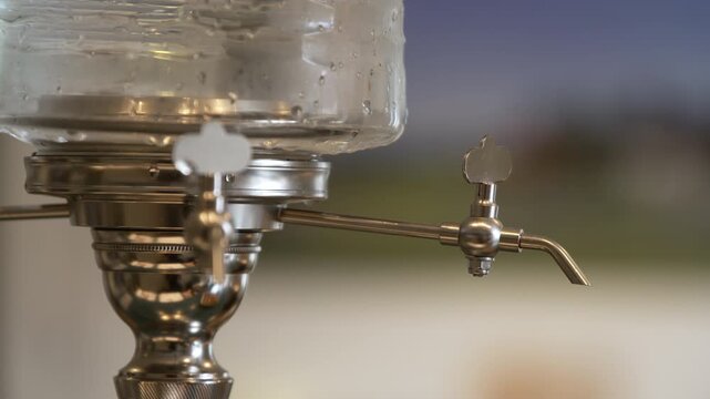 Traditional absinthe fountain close-up with blurred silhouette in background