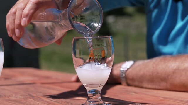 Preparing absinthe outdoors as water creates louche effect in glass