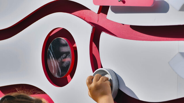 Childs hand playing with an interactive red and white modern educational exhibit